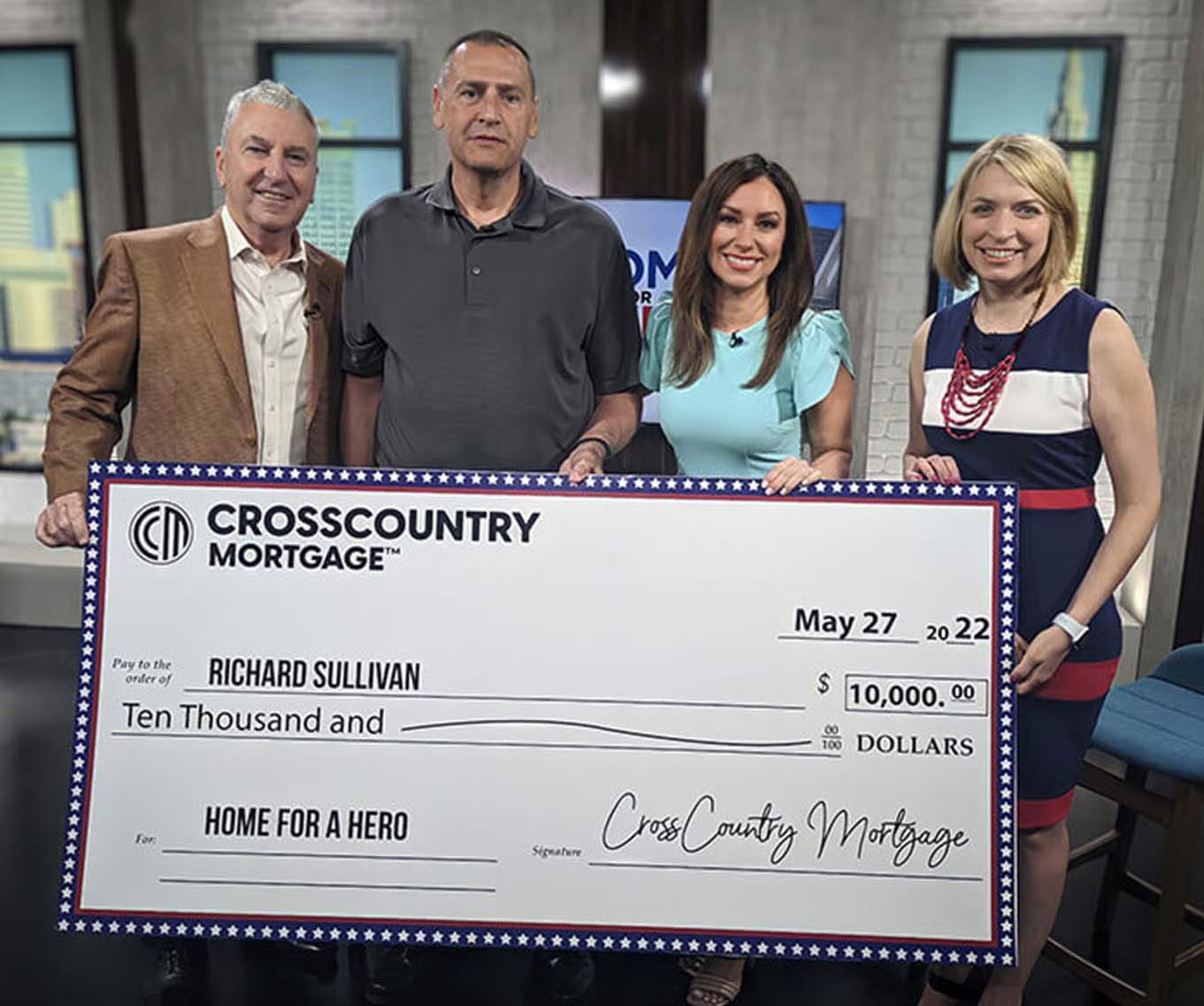 Homes for Hero winner, Rick Sullivan, holding his large check with Alicia Gauer and Fox 8 anchors