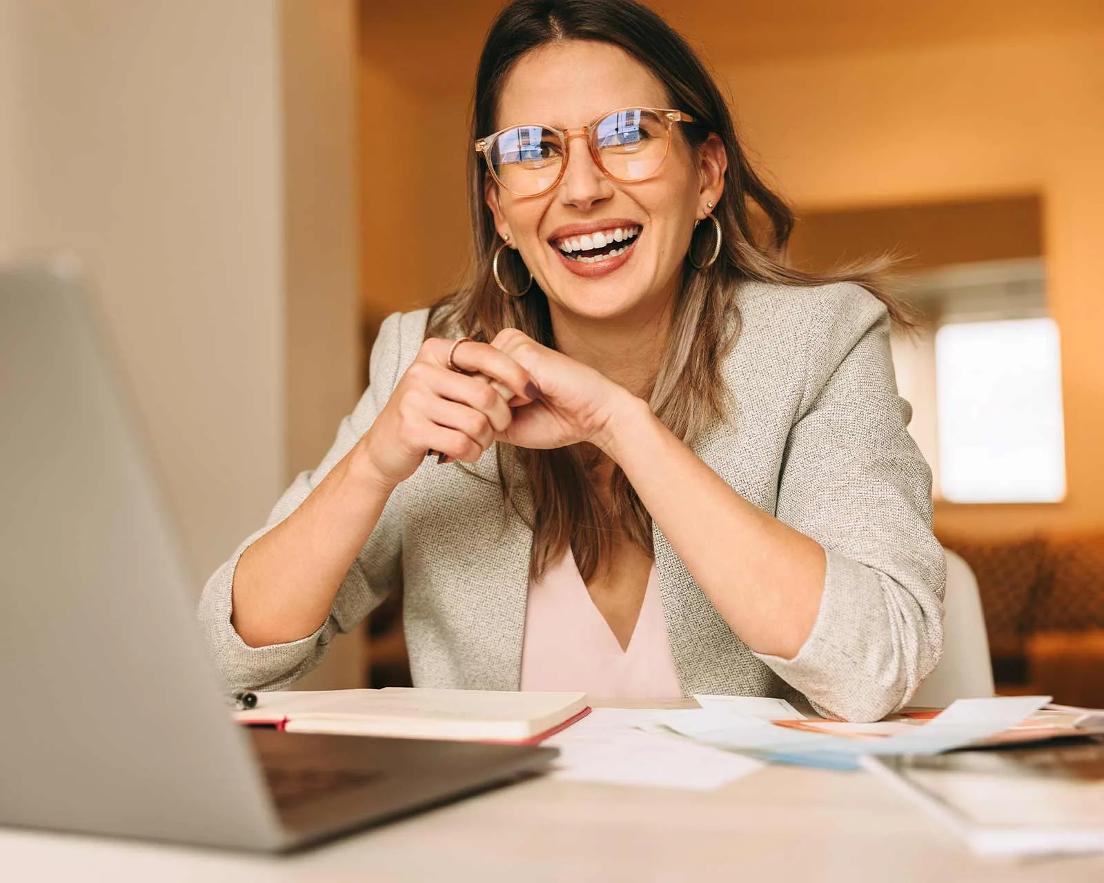 Woman sits at desk in front of computer researching refinance mortgage loans.