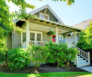 A craftsman-style house with a red front door and green yard, representing a typical home a buyer might purchase with an FHA loan.