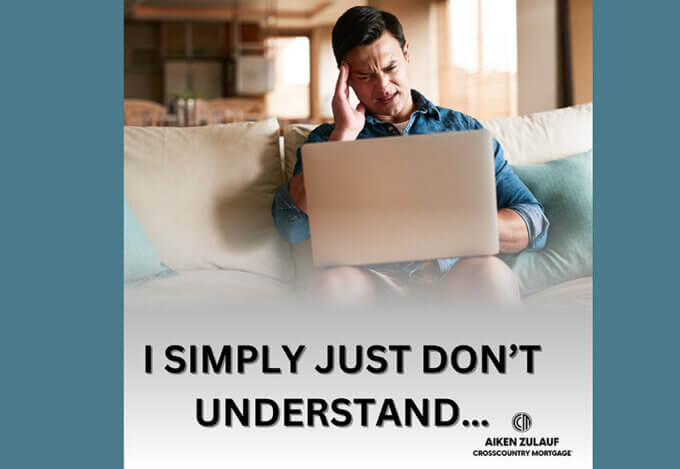 A man sitting on a couch looking confused at his laptop.