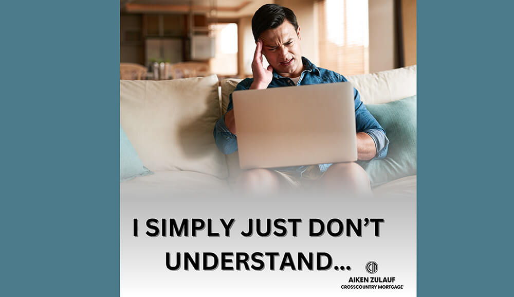 A man sitting on a couch looking confused at his laptop.