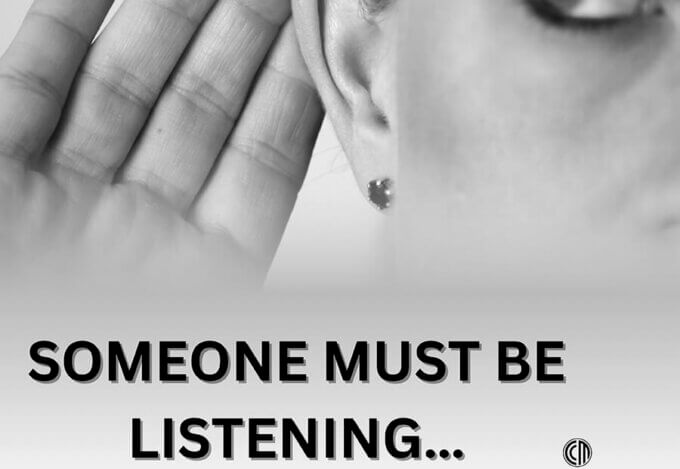 A woman holding her hand up to her ear.