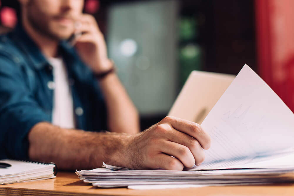 selective focus of a man holding documents on desk