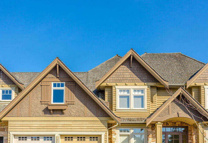 The front of a house with a gable roof and a clear blue sky in the background.