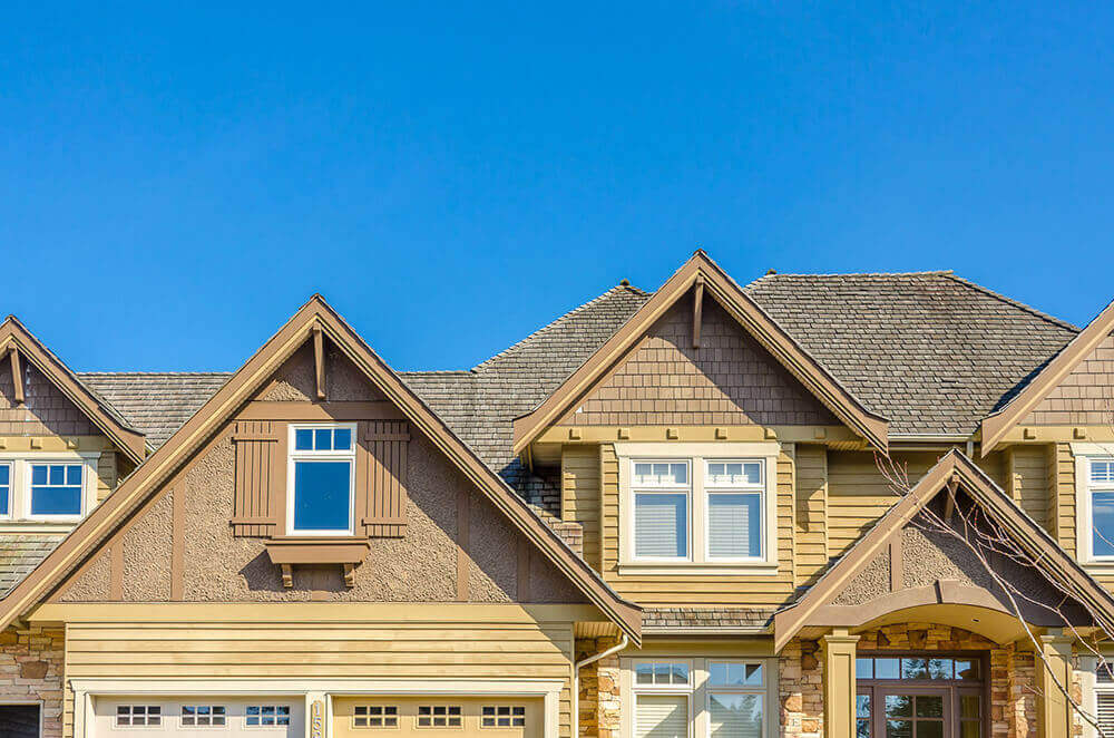 The front of a house with a gable roof and a clear blue sky in the background.