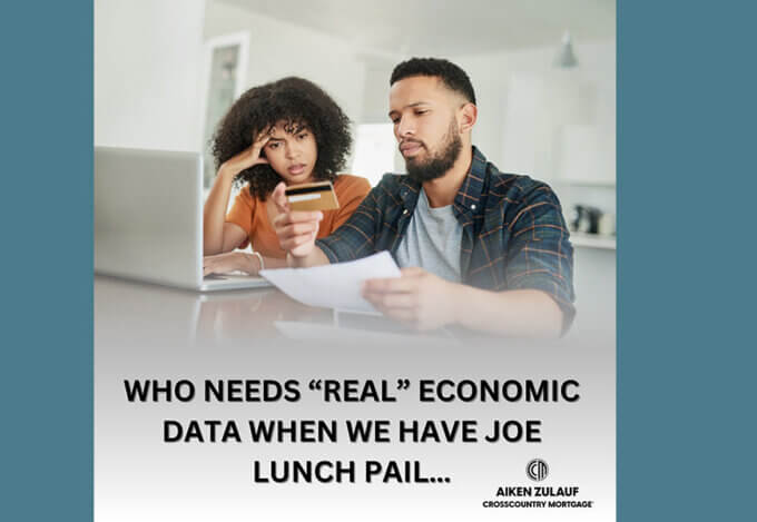 A man and a woman sitting at a table. Looking at papers and a laptop.