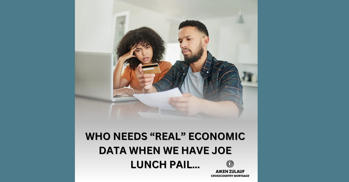 A man and a woman sitting at a table. Looking at papers and a laptop.