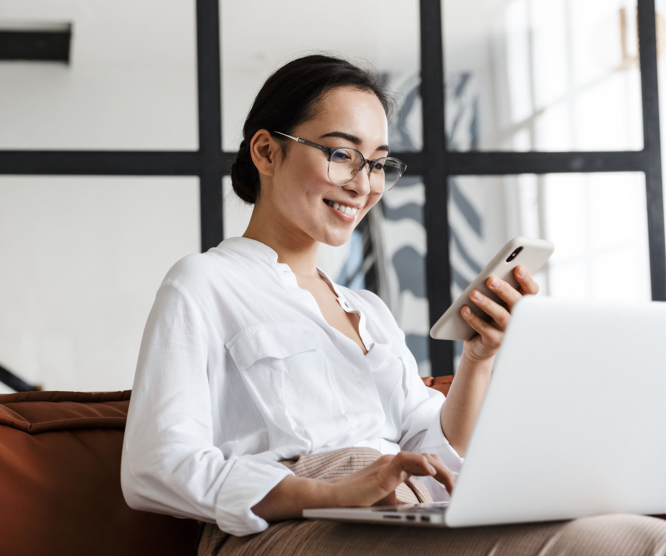 Woman sitting on coach reads a credit report on her cell phone.