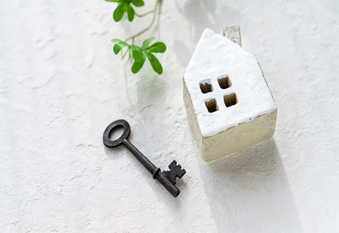 a small house trinket, sitting next to a key on a table.