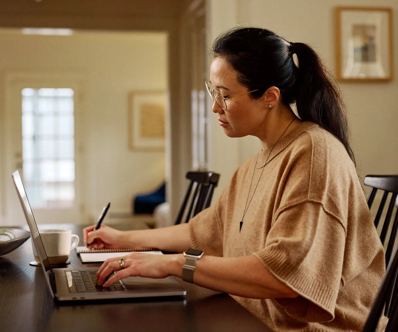 Woman reviewing loan details and writing notes about annual percentage rate (APR) at her desk.