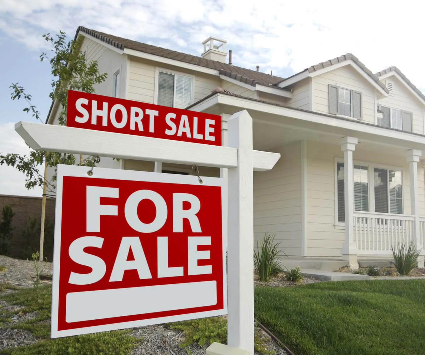 For sale sign in front of a home with “short sale” displayed on the sign.