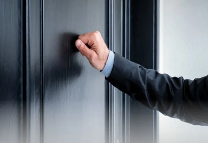 An arm reaching out and knocking on a door.