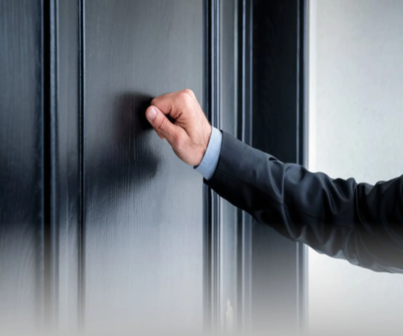 An arm reaching out and knocking on a door.