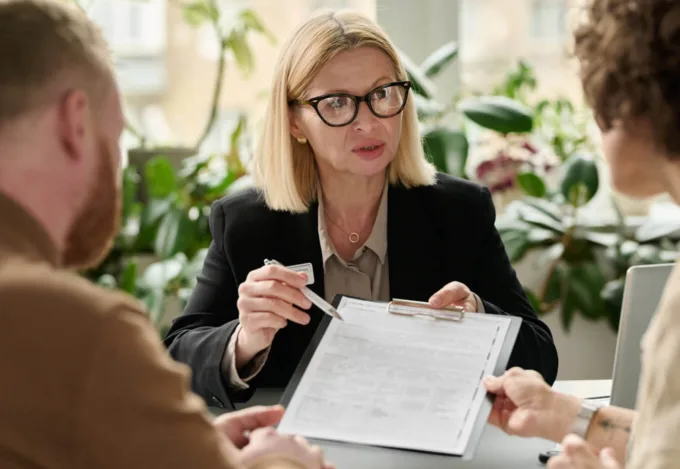 Mortgage professional explaining a deed of trust document to a couple during a home loan closing meeting.