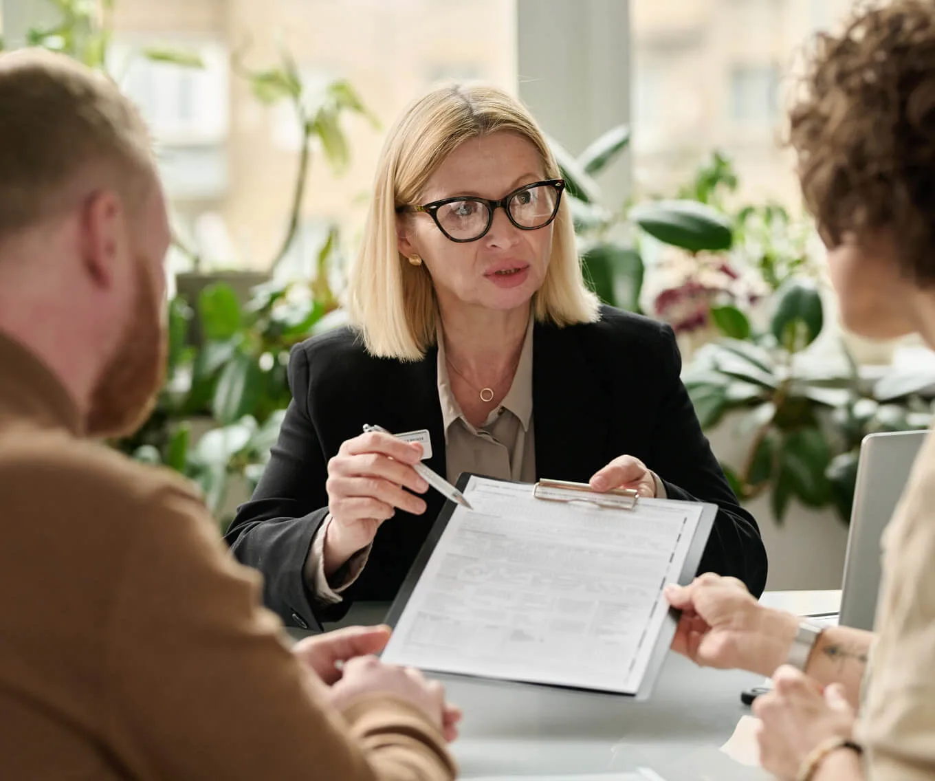 Mortgage professional explaining a deed of trust document to a couple during a home loan closing meeting.