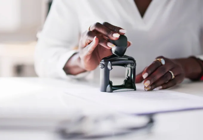 Notary signing agent stamping a document during a mortgage loan closing appointment.