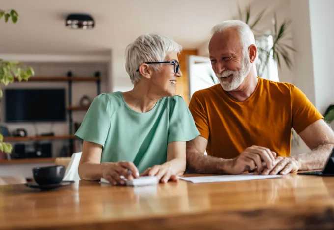 Senior homeowners smiling and reviewing paperwork together, illustrating 2026 housing trends and the rise of equity-rich buyers.