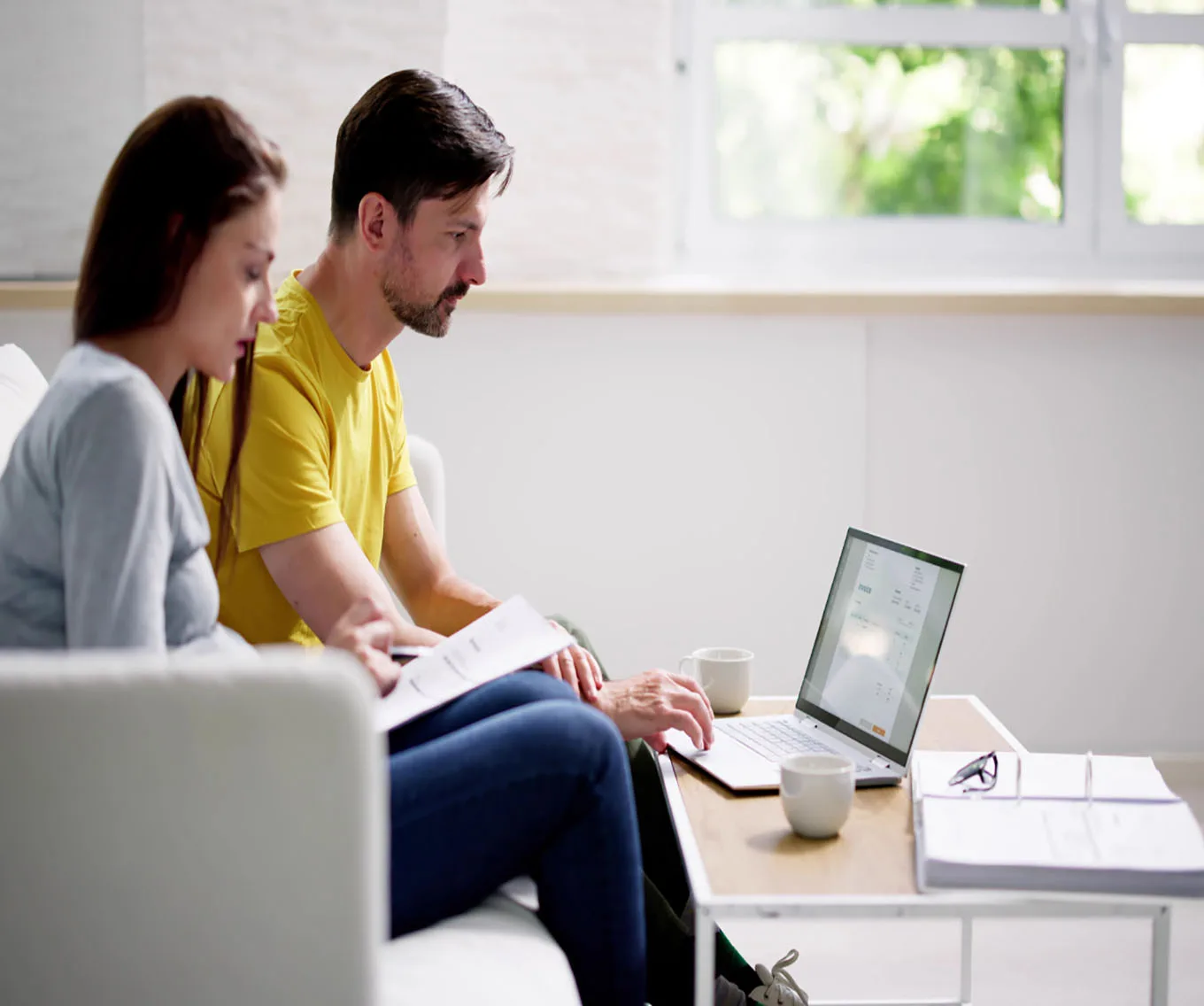 A couple sitting in their living room, researching down payment options.