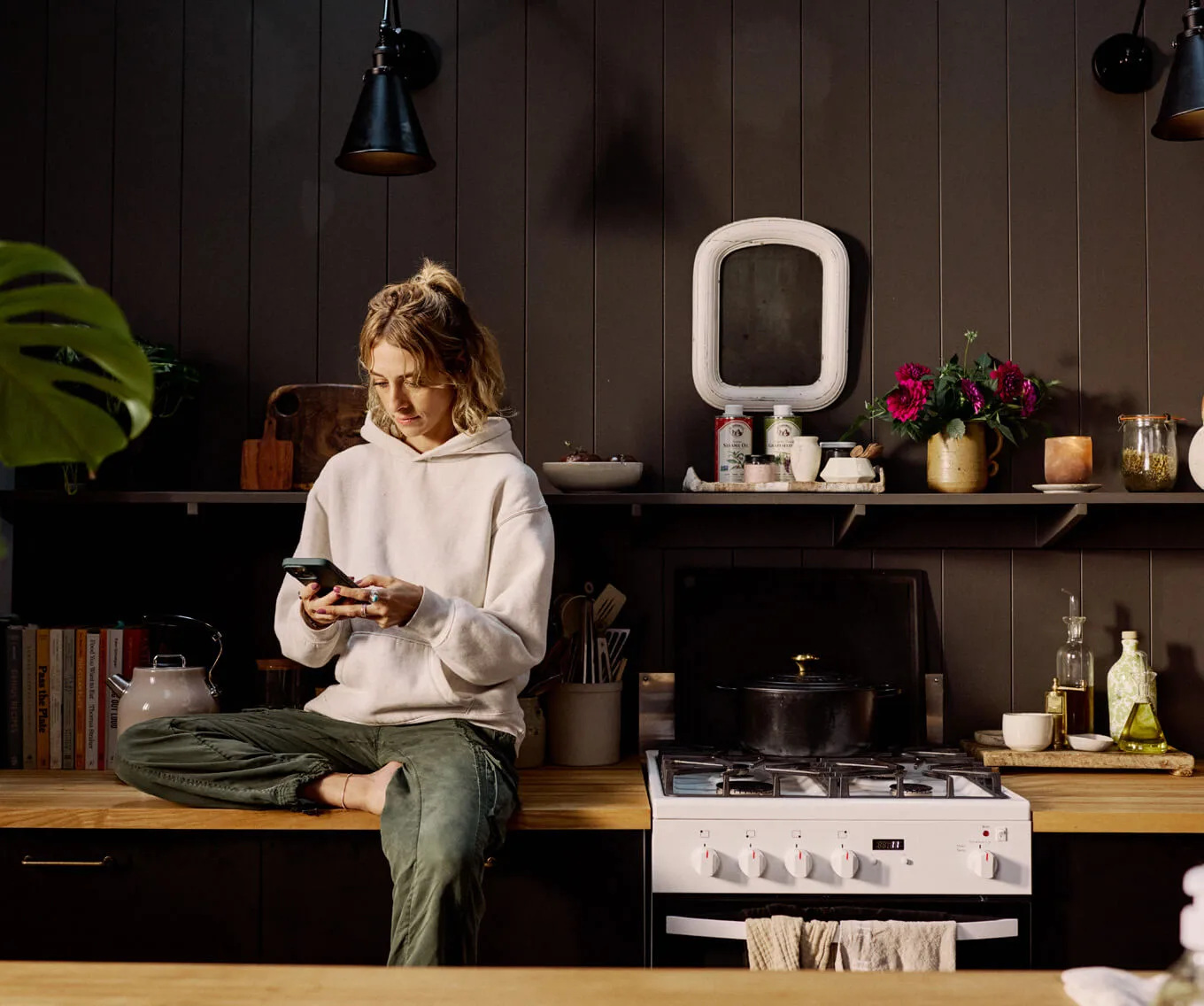 Homebuyer sitting in a modern kitchen reviewing information on a phone, representing key questions to ask when buying a house and preparing for the homebuying process