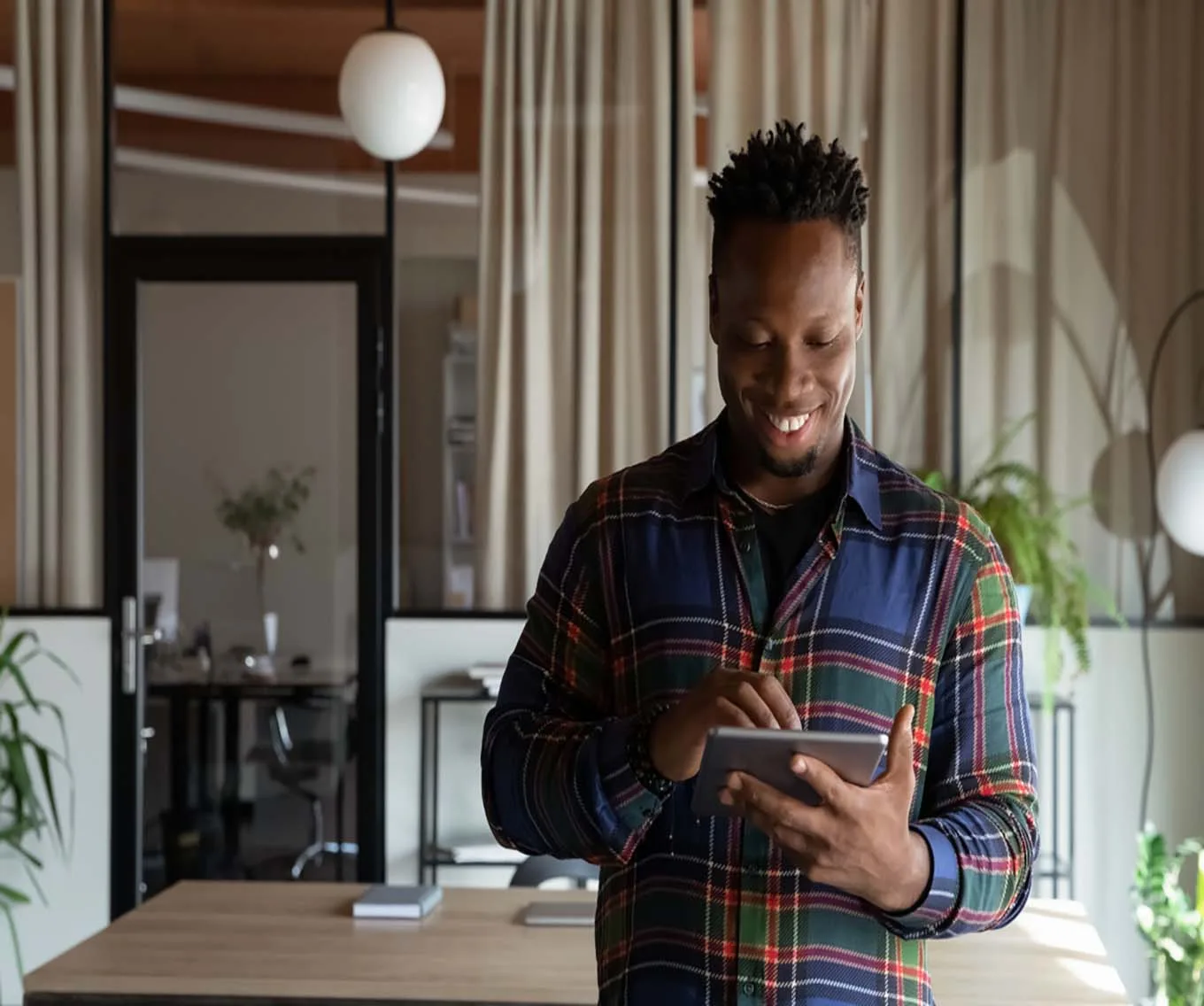 A man standing in front of a table. He is looking at a tablet researching DSCR loans.
