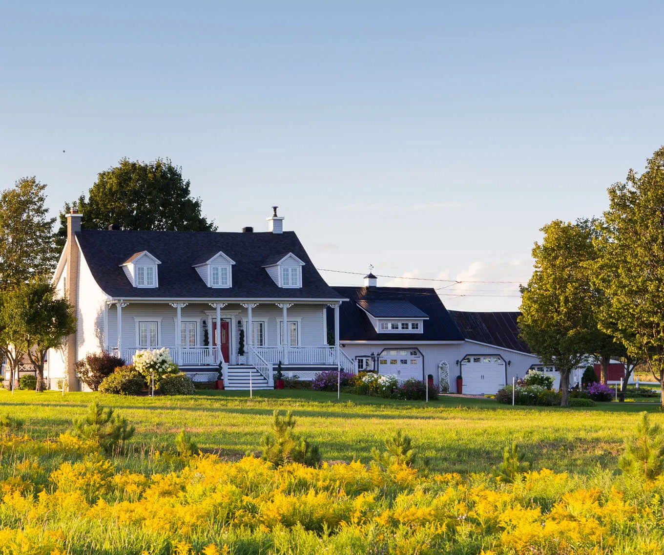 White house in a rural area surrounded by open land and trees, representing USDA loan-eligible homeownership opportunities.