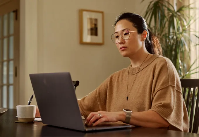Woman sitting at a laptop reviewing finances and loan information related to refinancing a home equity loan.