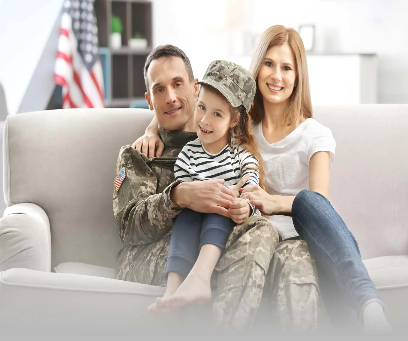 A Veteran sitting on the couch with his family. In their home they got with a VA loan