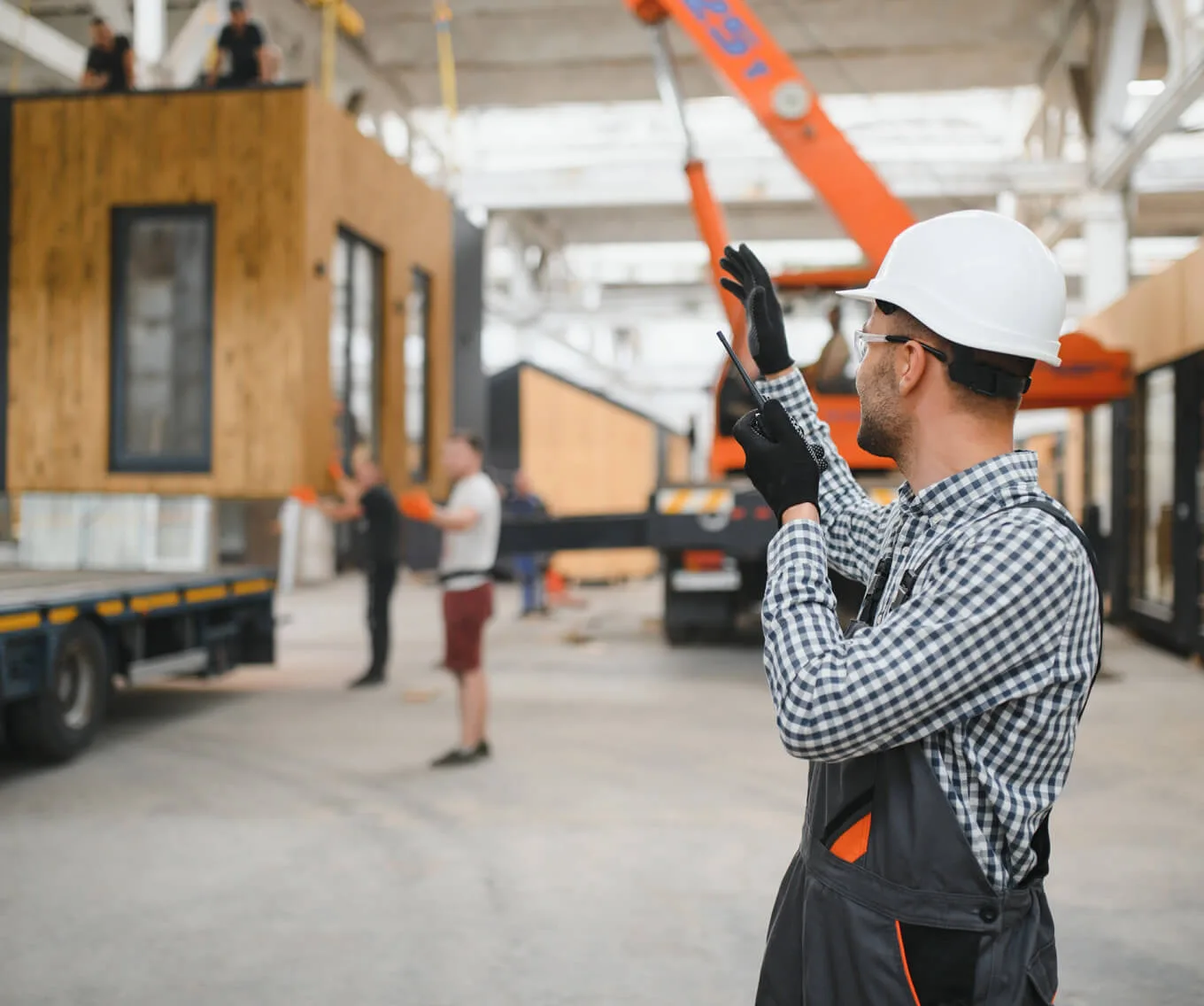 Construction worker guides a modular home inside a factory.