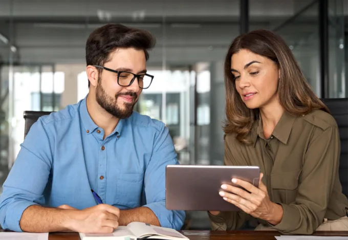 Mortgage loan officer and client reviewing information on a tablet while discussing mortgage rates and financing options.
