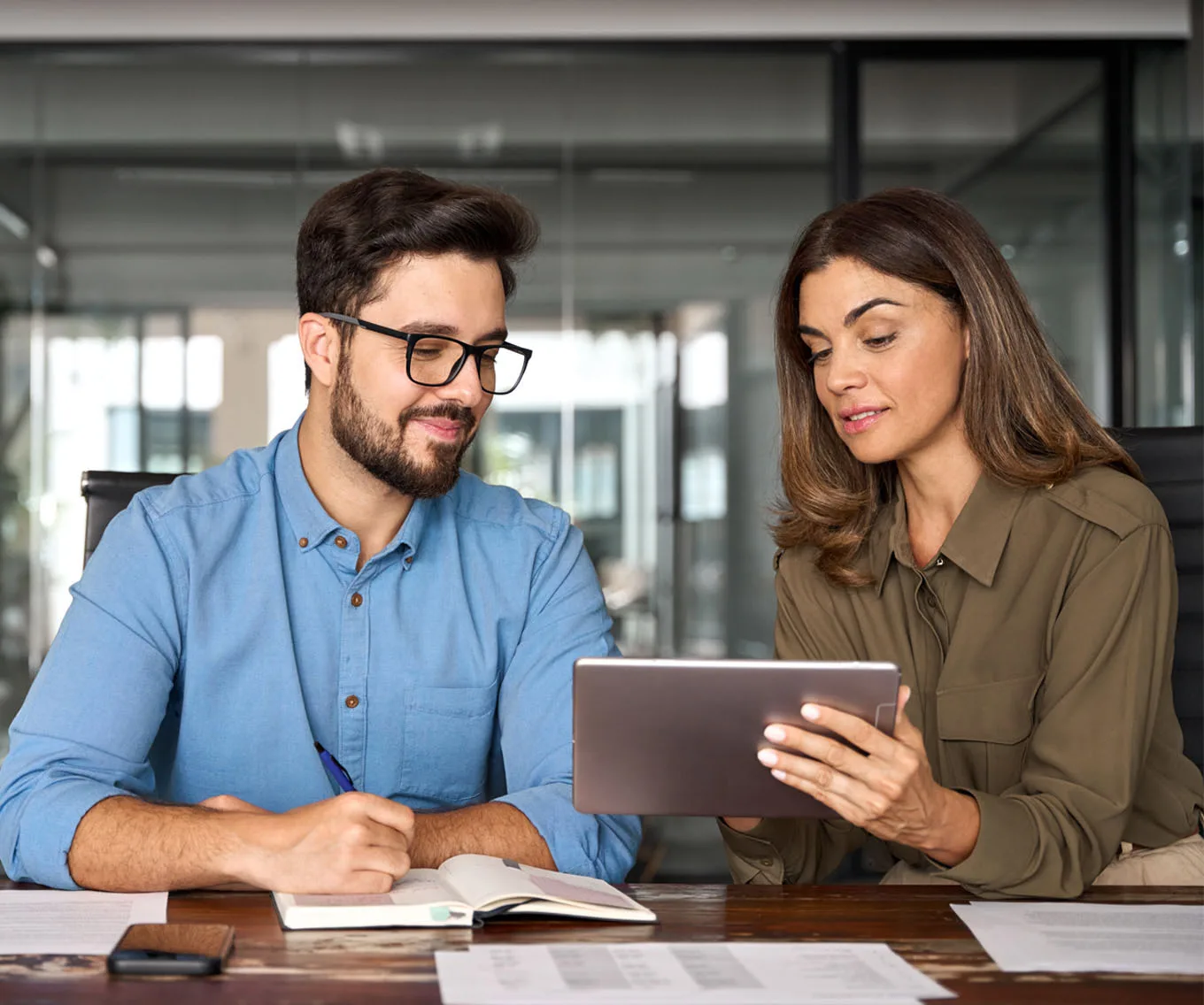 Mortgage loan officer and client reviewing information on a tablet while discussing mortgage rates and financing options.