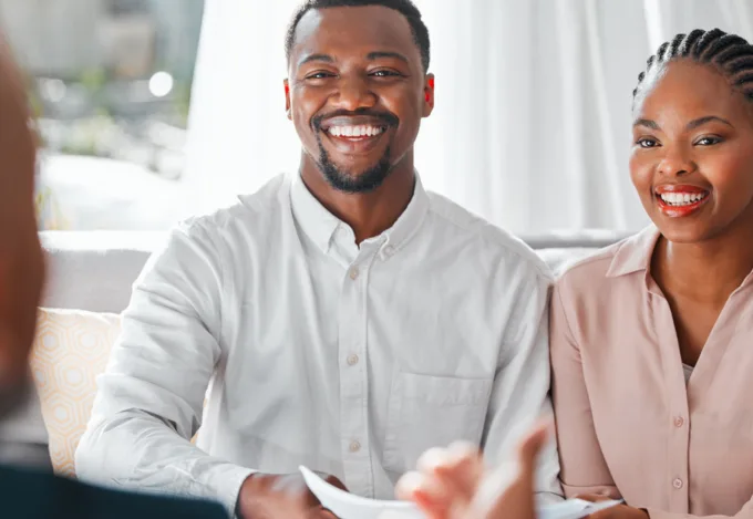Couple reviewing mortgage documents with a loan officer while preparing to use gift funds for a home purchase.