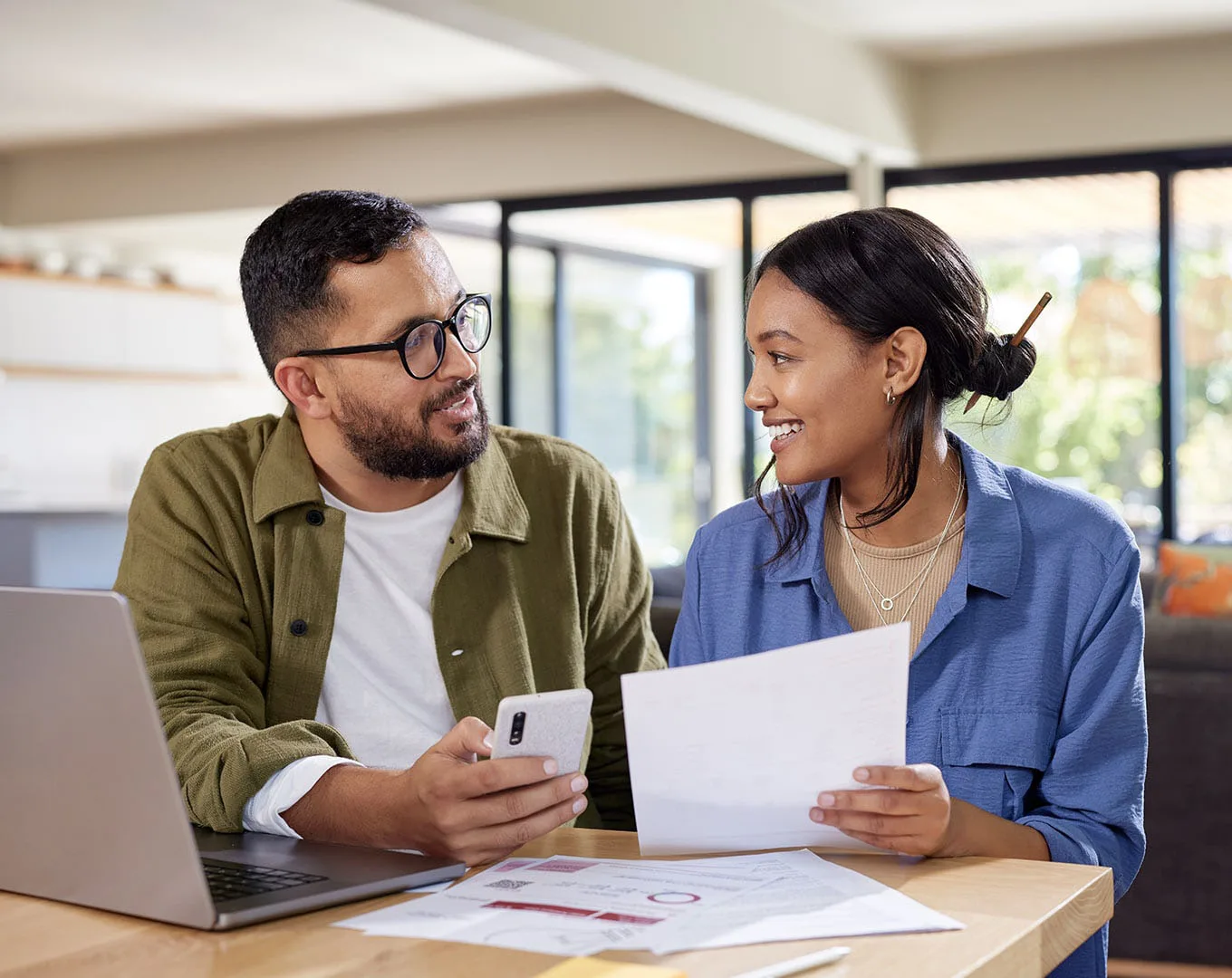 Couple reviewing financial documents together at a laptop while discussing credit scores and mortgage financing.