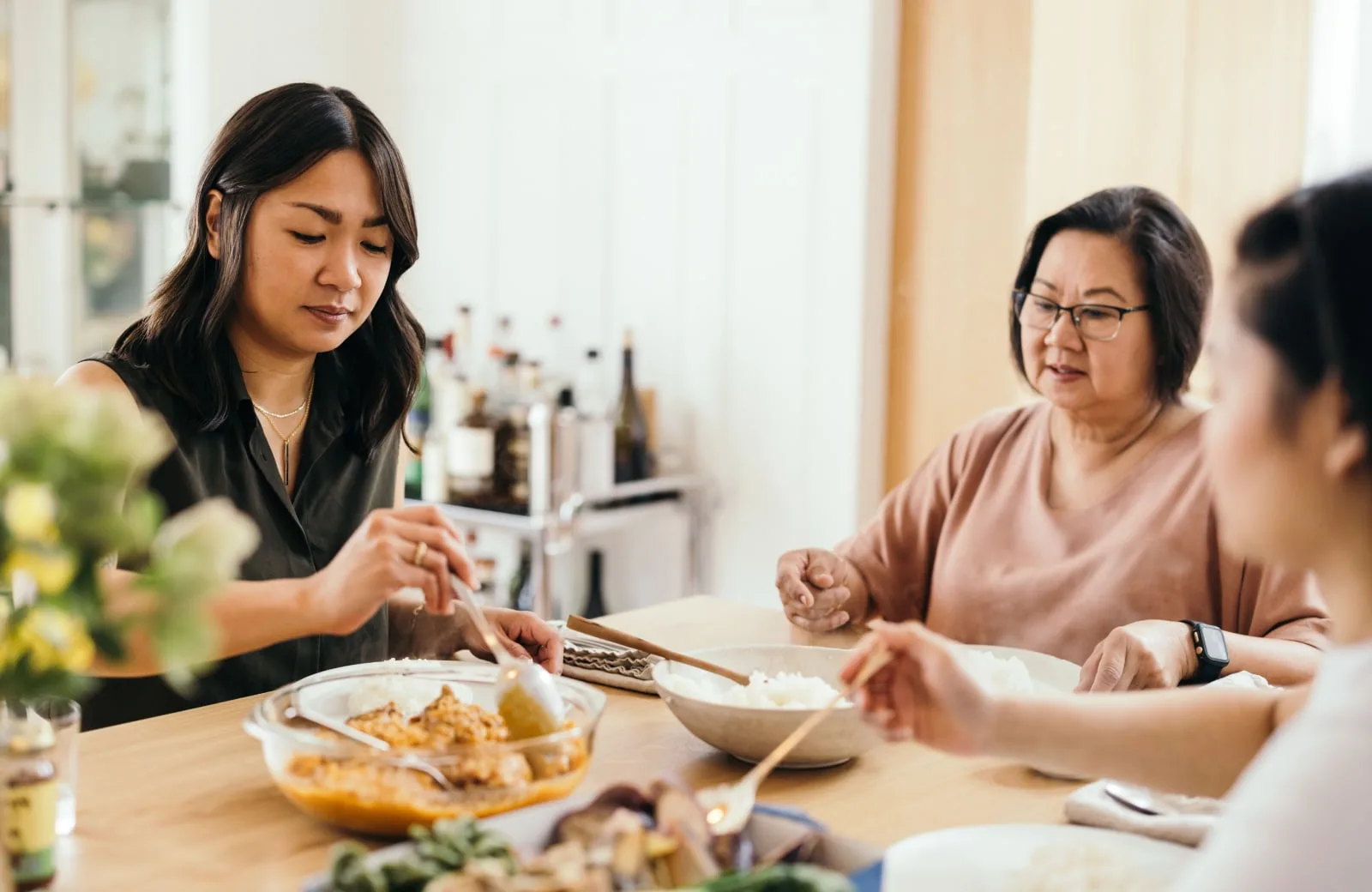 Three women sitting together and sharing a meal at a dining table.